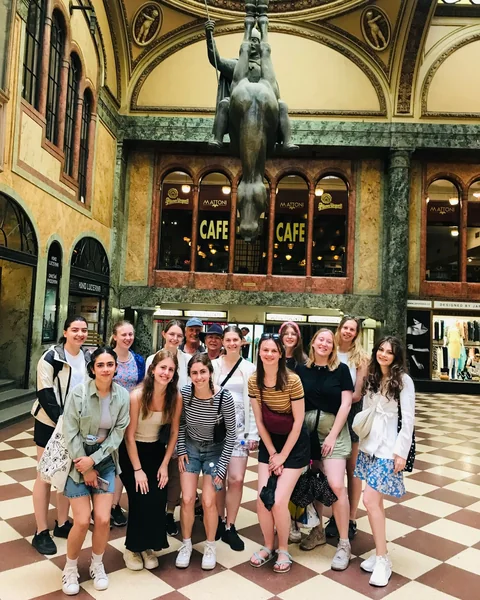 Tour guests beneath the hanging upside-down horse sculpture inside Lucerna Palace.