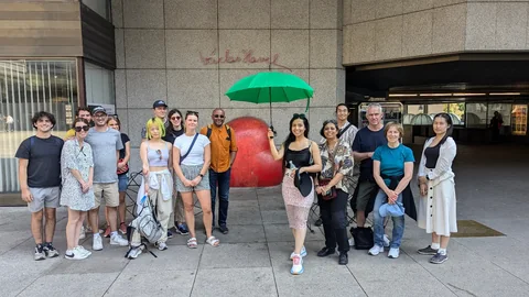 Tour guests with a green umbrella beside the red heart sculpture on Vaclav Havel Square.